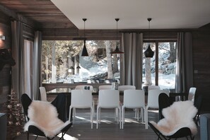 Un comedor moderno con techo de madera, ventanas grandes y sillas blancas.