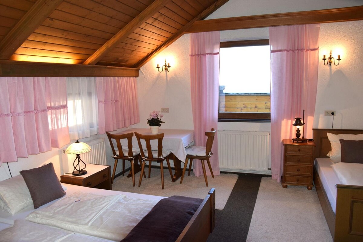 Une chambre à coucher comprenant un lit, une table de chevet, une lampe, une commode et une vue sur l’extérieur.