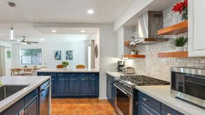 A modern kitchen with dark blue cabinets, white countertops, and a stainless steel range hood.