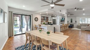 A spacious living area with a dining table, chairs, and a ceiling fan.