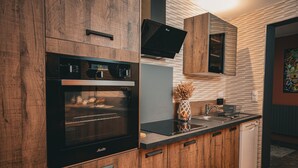 A modern kitchen with wooden cabinets, a built-in oven, a dishwasher, and a stainless steel countertop. - Maison de Campagne 4 Avec Terrain de Pétanque, Idéal Pour les Familles et Amis (Vireux-Wallerand)