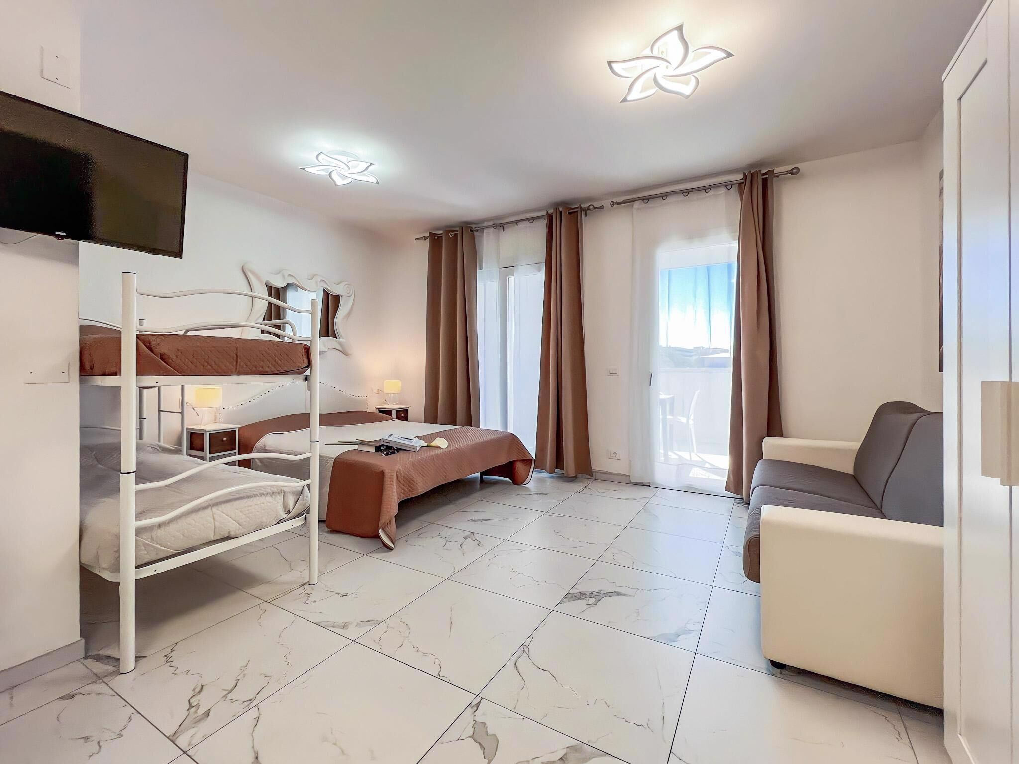 A hotel room with a bunk bed, a desk, a chair, and a TV.