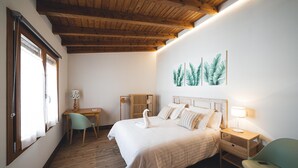 A bedroom with a wooden ceiling, a bed with white bedding, a desk with a chair, and a wall-mounted lamp. - Room 5 - Las Llanas. (Urda)