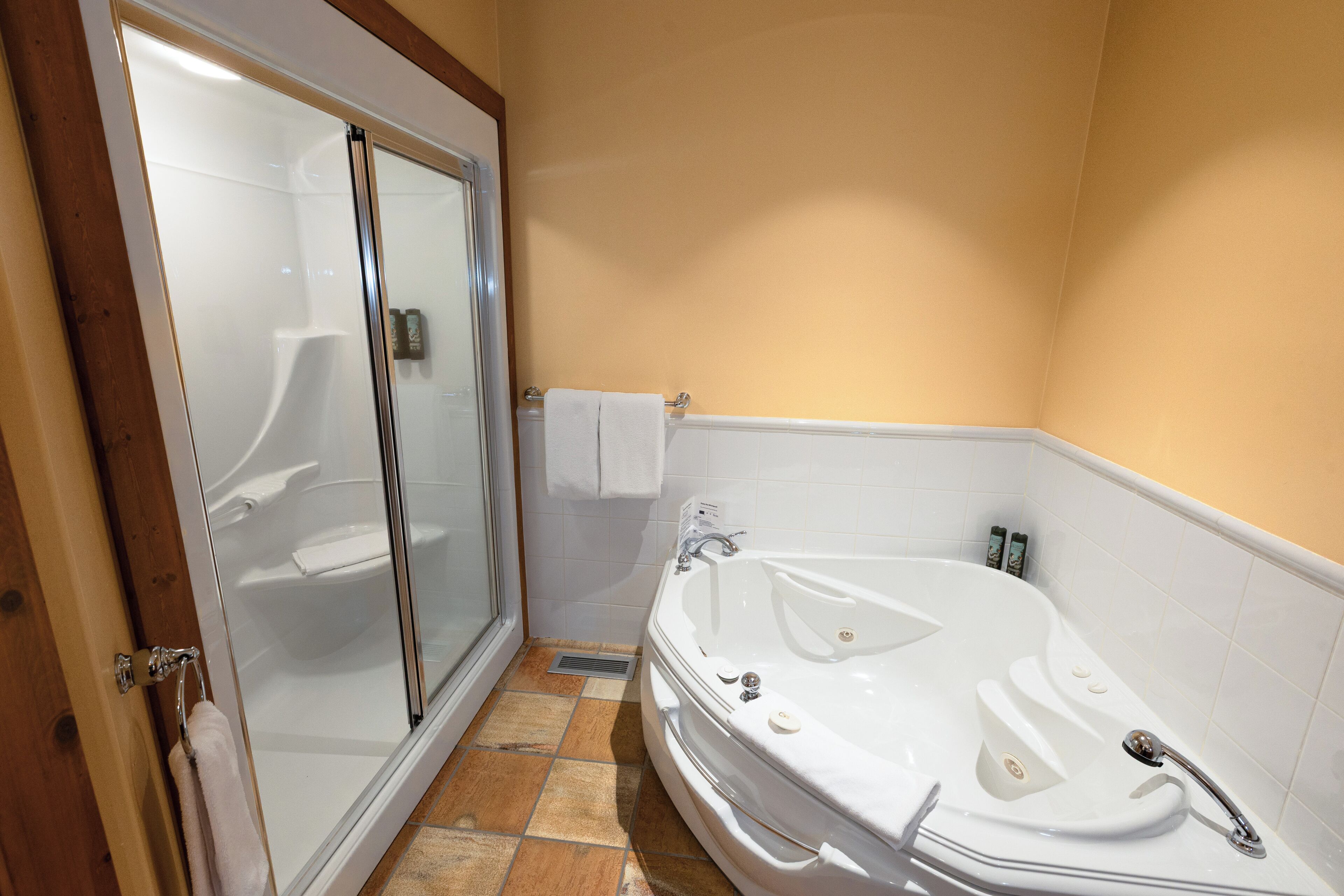 Une salle de bain avec une douche à parois de verre, une baignoire blanche et un sol carrelé.