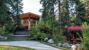 A lodge with a wooden exterior, stone foundation, and a stone staircase leading to the entrance. - Mike Wiegele Helicopter Skiing (Blue River)