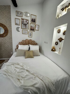 A bedroom with a bed, wall decor, and a window.