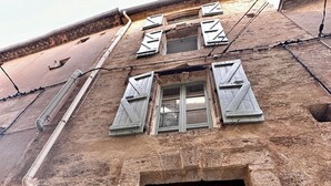 A rustic building with a large wooden door marked with the number 16, a small window with shutters, and a brick facade. - Cocon Cosy & Chaleureux à Pézenas: Chez Roméo (Pézenas)