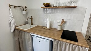 A compact kitchen with a wooden countertop, a sink, a small refrigerator, and a shelf with glasses and a bowl. - Cocon Cosy & Chaleureux à Pézenas: Chez Roméo (Pézenas)
