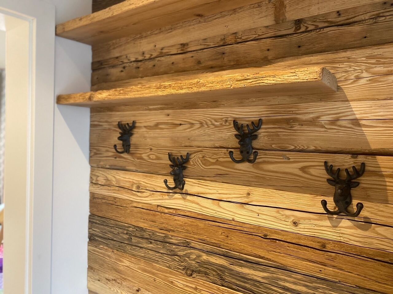 Una pared de madera con tres ganchos en forma de cabeza de animal negro.