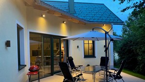 An outdoor patio with a dining table, chairs, and an umbrella.