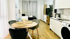 A modern kitchen with white cabinets, a microwave, and a washing machine. There is a dining area with a round table and chairs. - A (VA070.2.4) TH Mediterranean Suites 4 (Valencia / València)