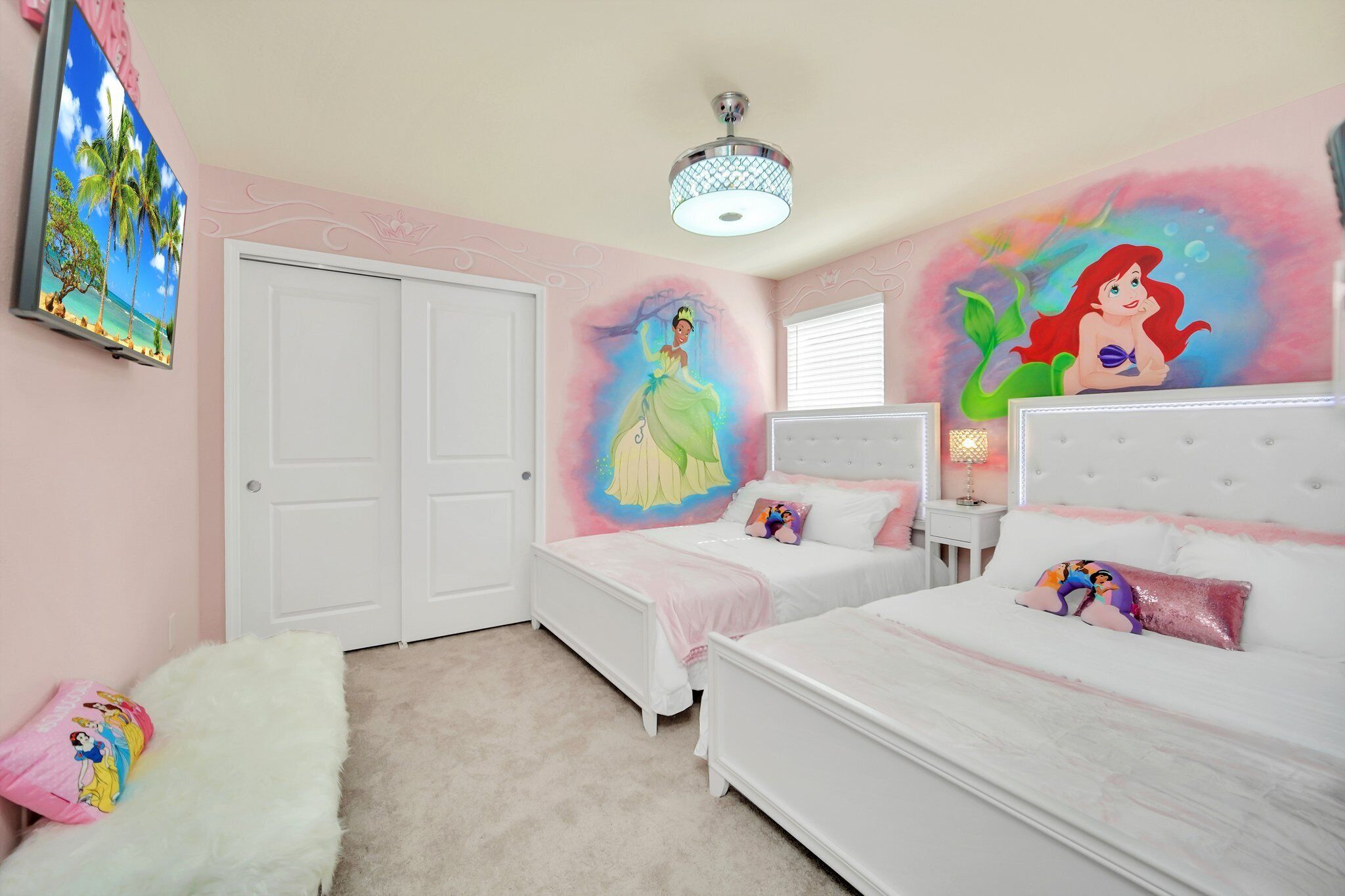 Un dormitorio con dos camas, un televisor y un mural de una sirena.
