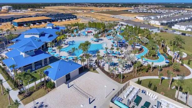 Eine Vogelperspektive eines Resorts mit mehreren Swimmingpools, Palmen und einem großzügigen Gebäude mit blauem Dach.