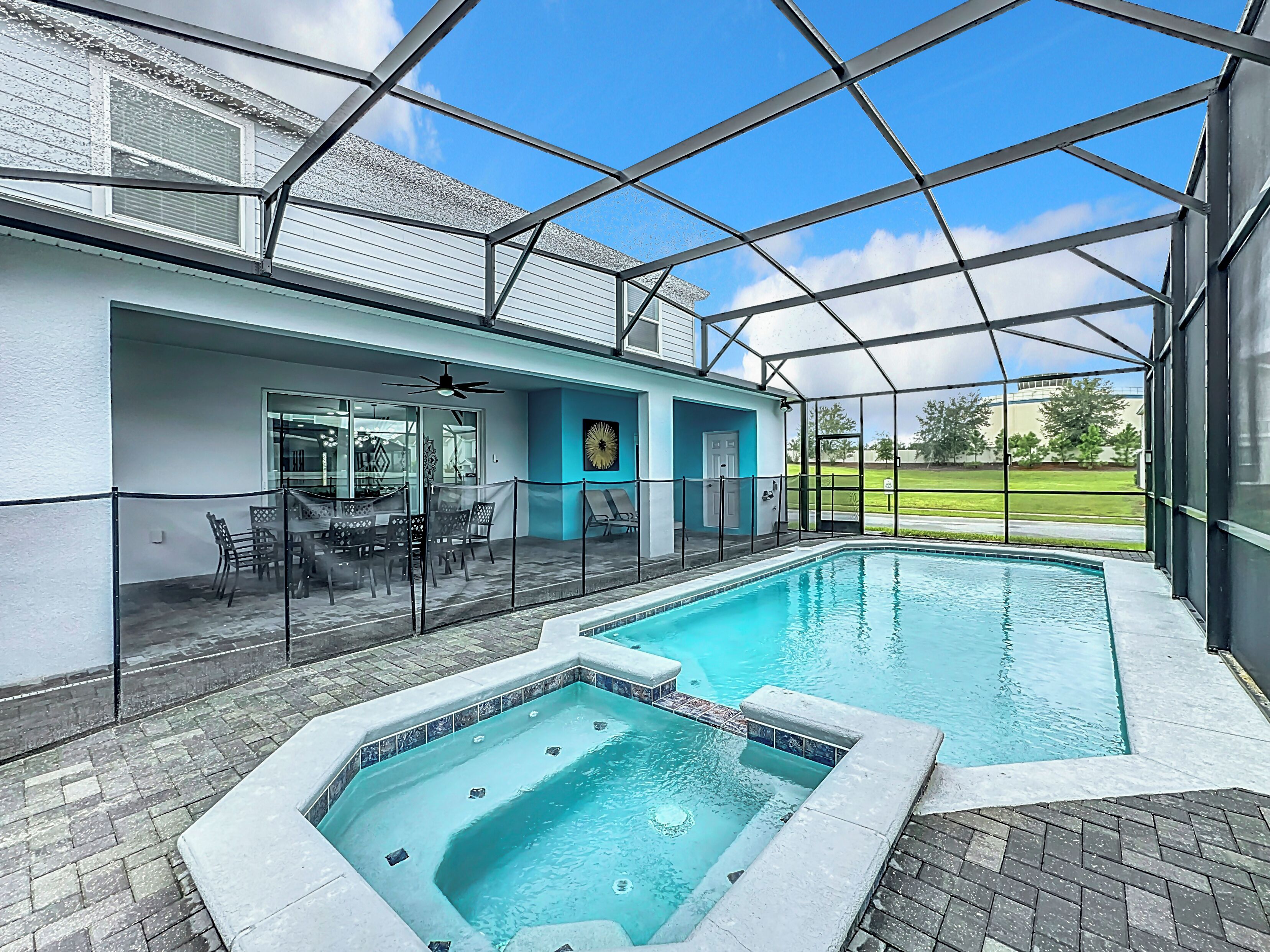 Una piscina interior con cerramiento de vidrio, un área de patio con asientos y vistas del paisaje circundante.