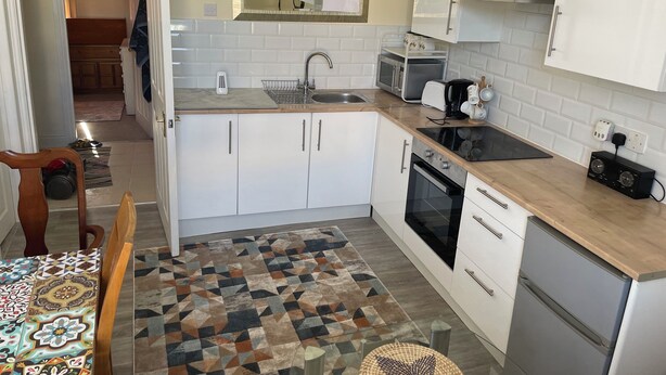 A compact kitchen with white cabinets, a microwave, a stove, and a sink.