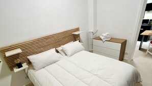 A neatly arranged bedroom with a large bed, a wooden headboard, a bedside table, and a small dresser. - Ludo’s Flat Bari Center  (Bari)