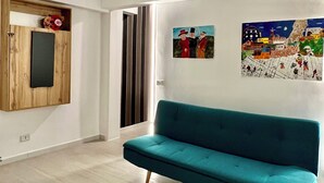 A modern living room with a teal sofa, wooden cabinet, and artwork on the walls. - Ludo’s Flat Bari Center  (Bari)