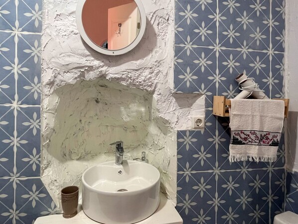 Une salle de bain avec un lavabo blanc, un miroir et un porte-serviettes.