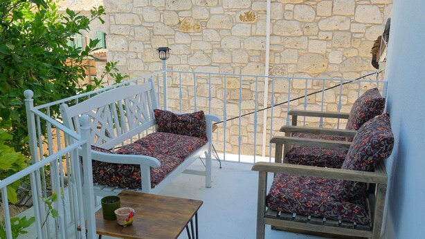 A balcony with a white railing, a wooden table, and two patterned sofas. - Eskikent Alaçatı (Cesme)