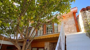 A stone building with a wooden balcony overlooking a garden. - Eskikent Alaçatı (Cesme)