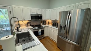 A modern kitchen with white cabinets, stainless steel appliances, and a wooden floor.