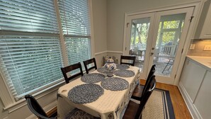 A dining room with a table set for four, featuring blue and white patterned placemats and a decorative vase.