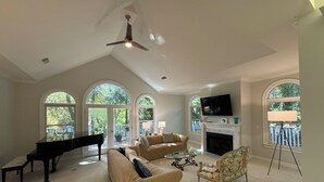 A spacious living room with a grand piano, a fireplace, and a television.
