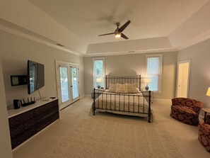 A bedroom with a bed, a dresser, a TV, and a ceiling fan.