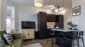 A modern kitchen with a dining area, a television, and a coffee machine. - Broughton Place (Liverpool)