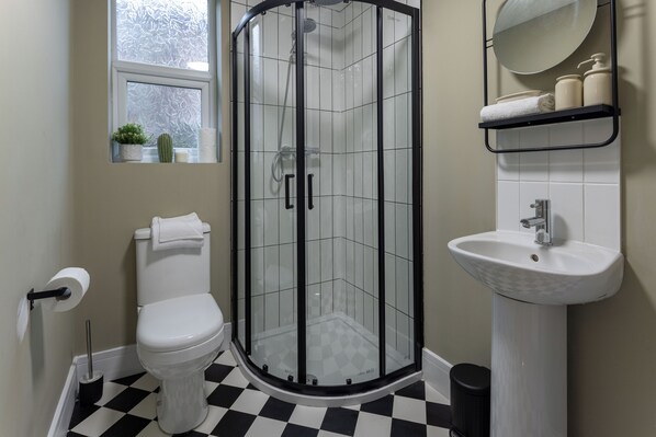 A bathroom with a white toilet, a glass-enclosed shower, a sink, and a window with a view. - Broughton Place (Liverpool)