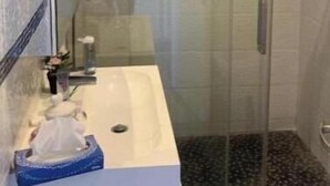 A bathroom with a glass-enclosed shower, a white sink, and a mirror. - La Villa Provençale (Mougins)