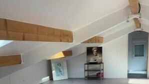 A spacious attic room with a sloped ceiling, exposed wooden beams, and a large window allowing natural light. - La Villa Provençale (Mougins)