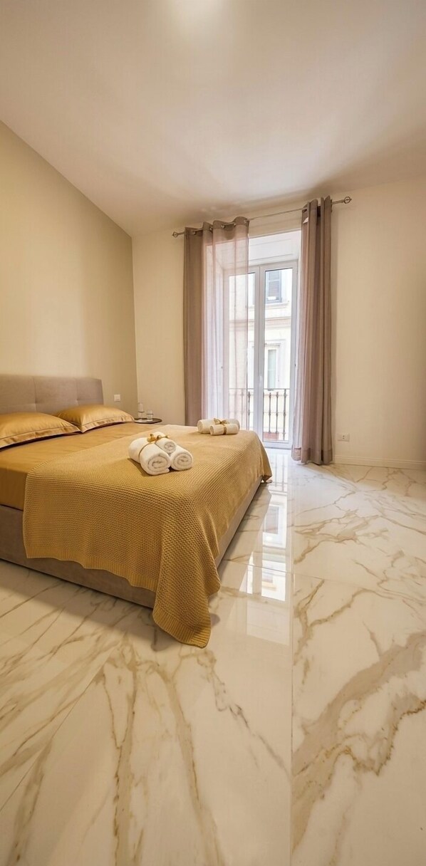 Habitación de hotel con cama, balcón y vista a edificios.