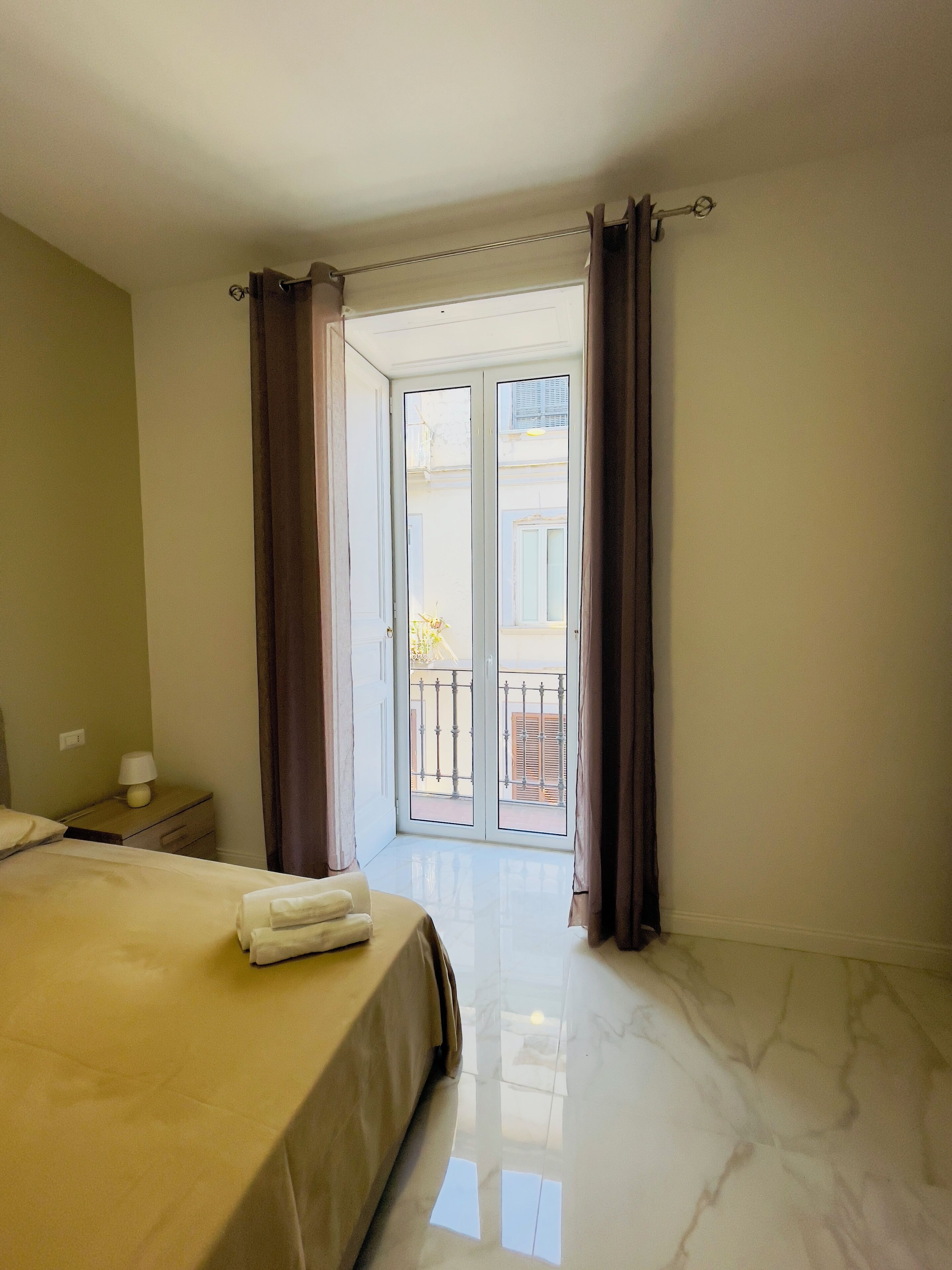 Een hotelkamer met een bed, een nachtkastje en uitzicht op het balkon.
