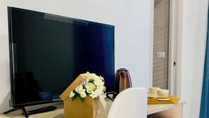 A modern office desk with a computer monitor, a white office chair, a coffee maker, and a small cabinet. - Nerisa Home (Napoli)