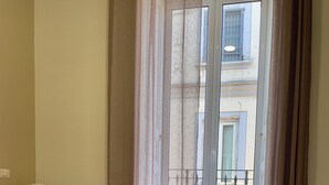 A hotel room with a bed, towels, a lamp, and a view of the outside balcony. - Nerisa Home (Napoli)