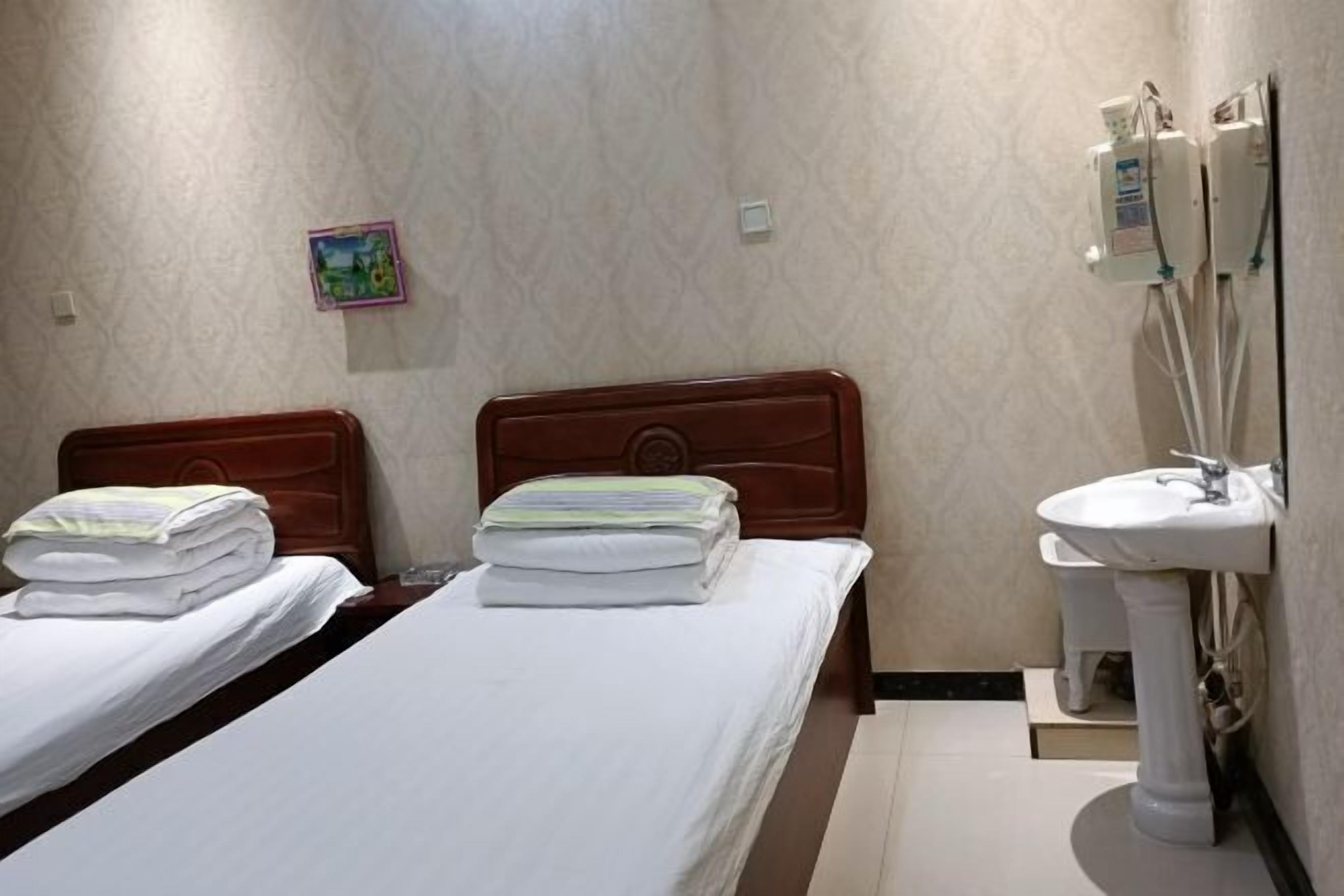 A hotel room with two beds, a bathroom with a sink, and a small decorative item on the wall.