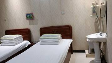 A hotel room with two beds, a bathroom with a sink, and a small decorative item on the wall.