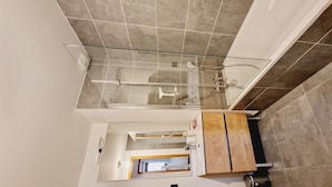 Un baño moderno con cabina de ducha de vidrio, tocador de madera y espejo.