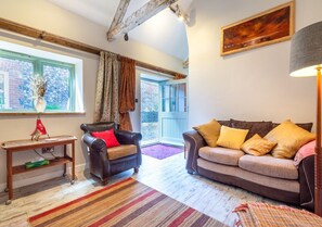 Relax in this inviting living room with a sofa, wooden table, and large window offering a view of lush greenery.