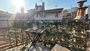 Une terrasse sur le toit, avec une table, des plantes en pot et une vue sur les bâtiments voisins.