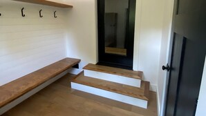 A hallway with a wooden bench, a black door, and a small set of wooden steps leading to a room. - Escape to The Clyde’s View Hideaway in Manchester, Vt. New Home  3 Bed 2 Bath (Manchester Center)