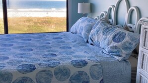 Ein Schlafzimmer mit großem Fenster und Blick auf Strand und Meer.