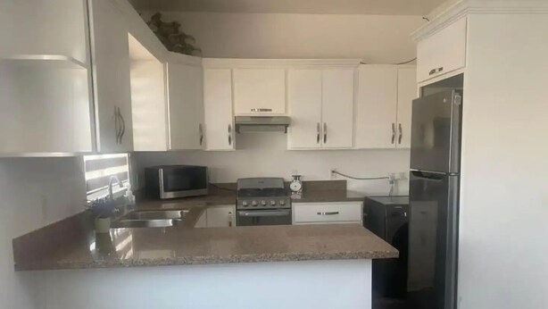 A modern kitchen with white cabinets, a granite countertop, a microwave, an oven, a refrigerator, and a dishwasher.