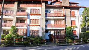 A multi-story building with balconies, a sign indicating a restaurant, and a gated entrance. - Ap in Capivari - Tirol31 By Temporada Férias (Campos do Jordão)