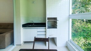 A compact kitchen with a sink, cabinets, and a window overlooking greenery.