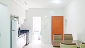 A bright kitchen with white cabinets, a stove, and a refrigerator. There is a dining area with a table and chairs.