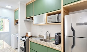A kitchen with a stainless steel refrigerator, a microwave, and a coffee maker on the countertop.