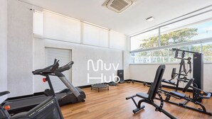 A gym with a treadmill, weight bench, and various exercise equipment.