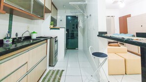 Una cocina estrecha con refrigerador, pileta y un pequeño comedor con una silla y cojines.